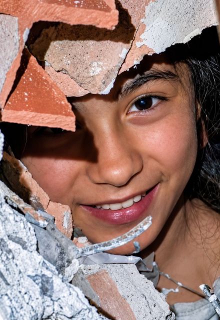 Retrato de una niña sonriendo a través de escombros