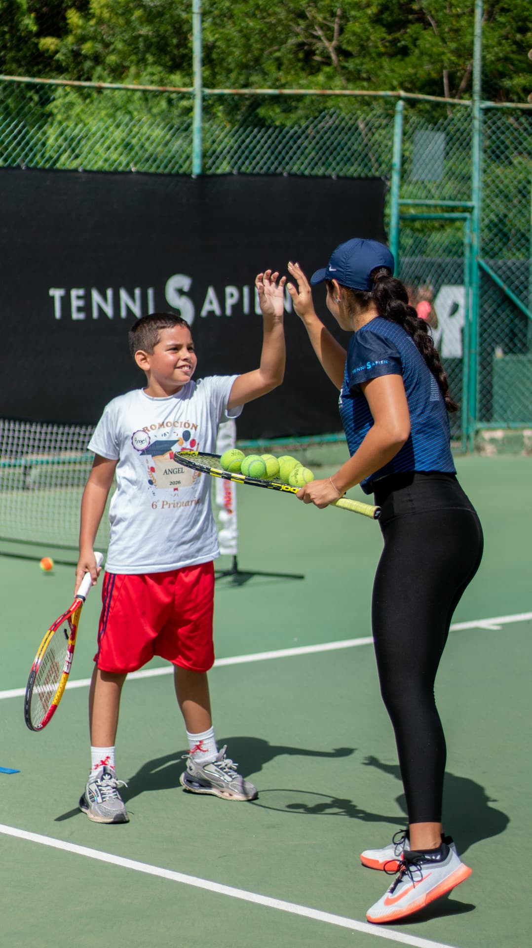 Niño chocando la mano con una entrenadora de TenniSapien