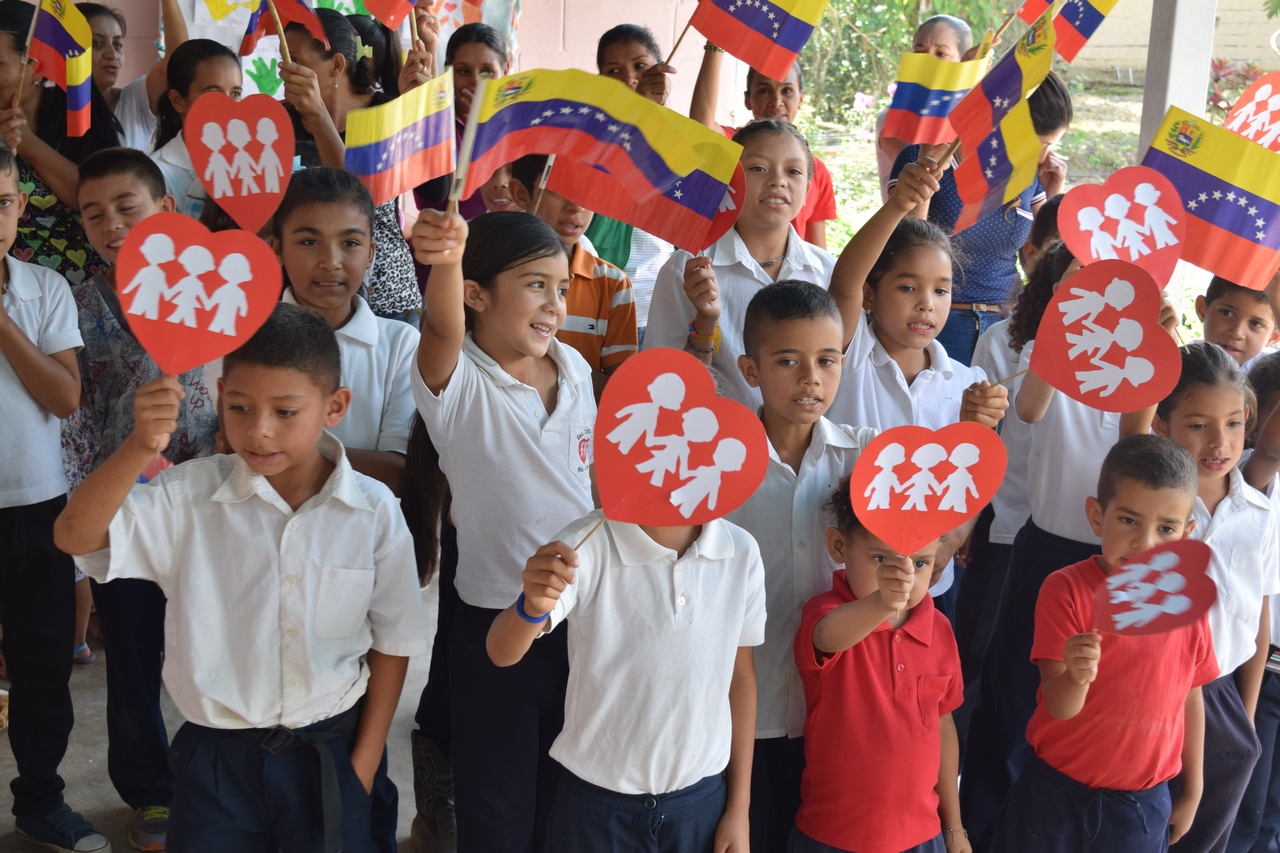 Niños de una comunidad aliada con banderas de Venezuela y corazones de papel
